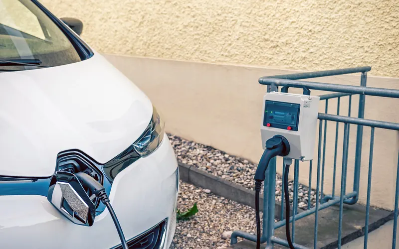 Carro elétrico conectado a um carregador de parede (wallbox) instalado junto à vaga